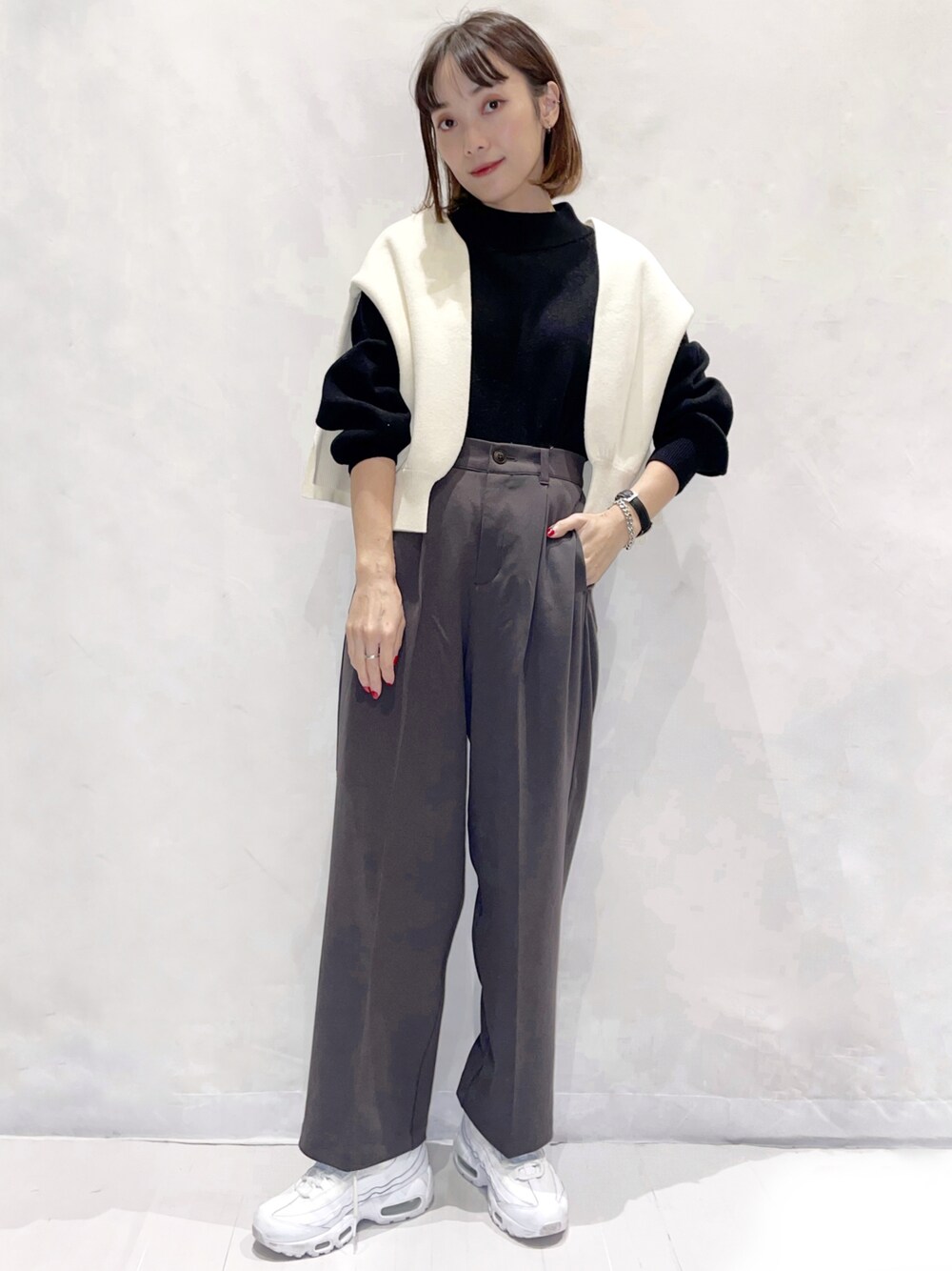 グレー系のスラックス、ブラック系のニット/セーター、ホワイト系のニット/セーターを着用したレディースの秋コーディネートの1枚目の写真