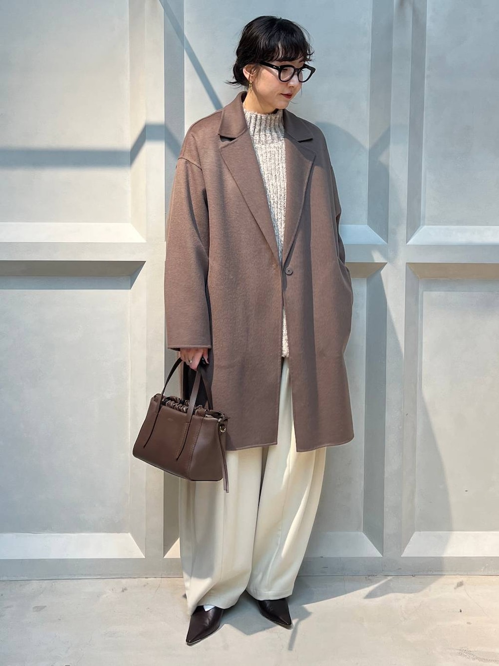 ホワイト系のその他パンツ、ベージュ系のニット/セーター、ブラウン系のチェスターコートを着用したレディースの秋コーディネートの1枚目の写真