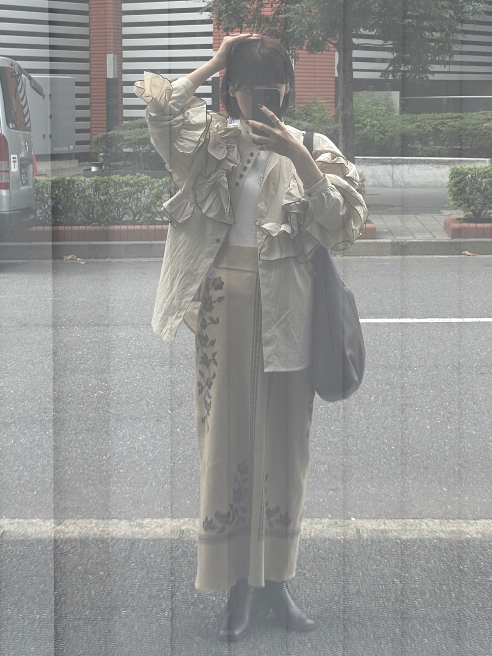 ホワイト系のトップス、ベージュ系のスカート、ブラウン系のトートバッグを着用したレディースの秋コーディネートの1枚目の写真