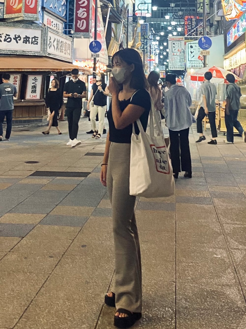 ブラック系のTシャツ/カットソー、ベージュ系のトートバッグ、ブラウン系のパンツを着用したレディースの冬コーディネートの1枚目の写真