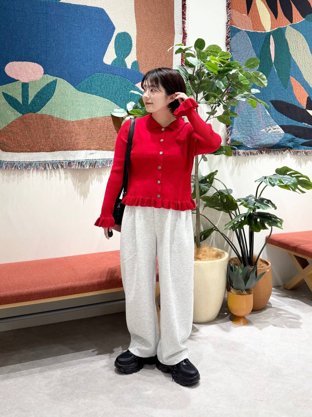 グレー系のスウェットパンツ、レッド系のニット/セーター、ブラック系のスニーカーを着用したレディースの秋コーディネートの1枚目の写真