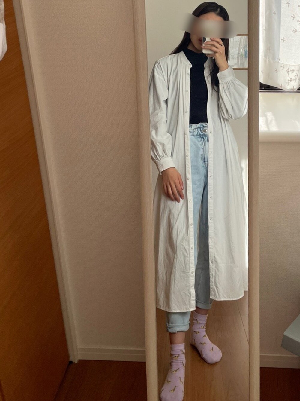 ホワイト系のシャツワンピース、ブルー系のデニムパンツ、ブラック系のトップスを着用したレディースの秋コーディネートの1枚目の写真