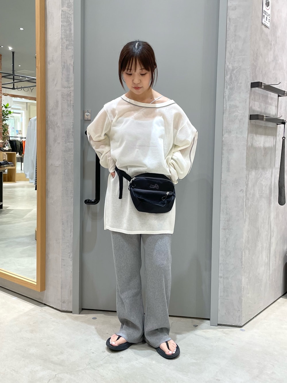 ブラック系のボディバッグ/ウエストポーチ、ホワイト系のニット/セーター、グレー系のその他パンツを着用したレディースの春コーディネートの1枚目の写真