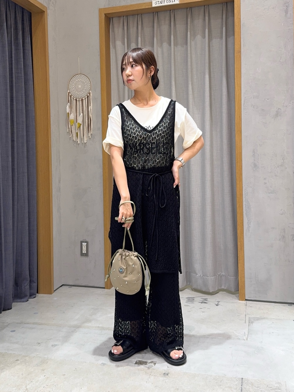 ブラック系のニット/セーター、ブラック系のその他パンツ、グリーン系のハンドバッグを着用したレディースの夏コーディネートの1枚目の写真