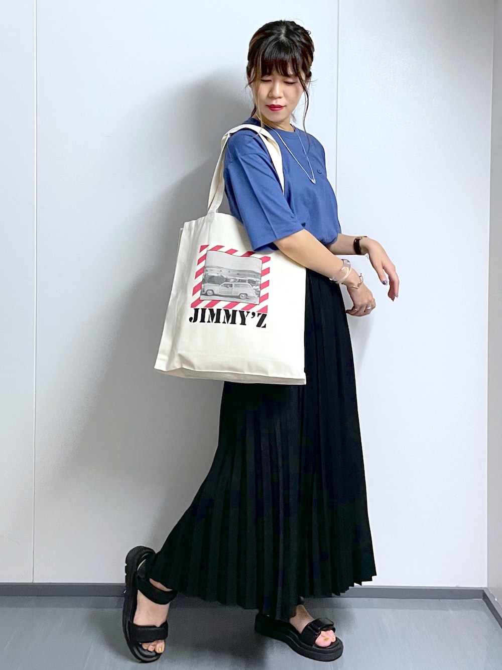 ブラック系のサンダル、ブラック系のスカート、ホワイト系のトートバッグを着用したレディースの夏コーディネートの1枚目の写真