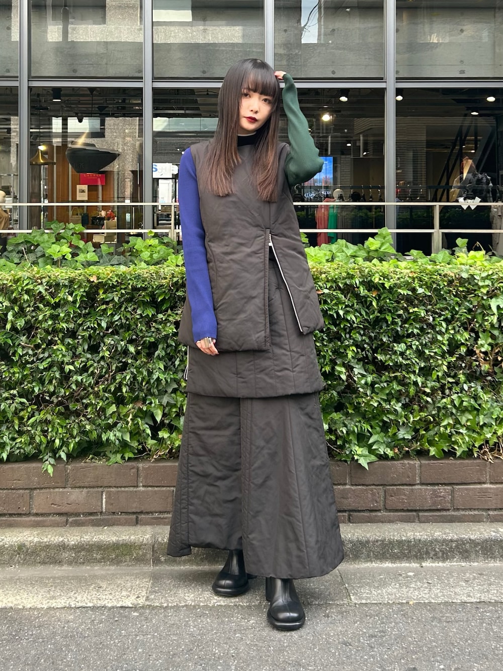 ブラック系のニット/セーター、ブラック系のスカート、ブラック系のダウンベストを着用したレディースの夏コーディネートの1枚目の写真