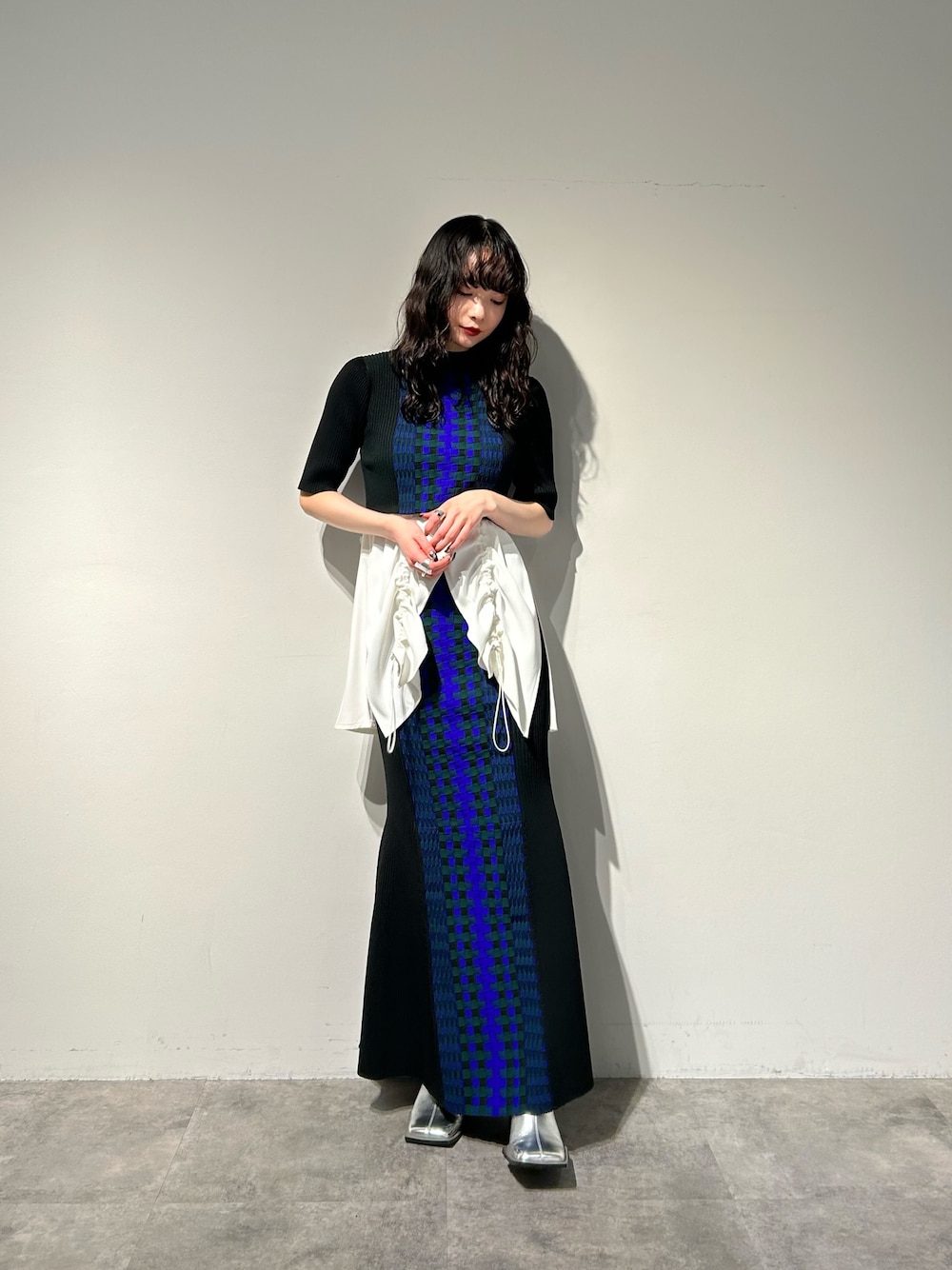 シルバー系のブーツ、ブラック系のスカート、ホワイト系のタンクトップを着用したレディースの冬コーディネートの1枚目の写真