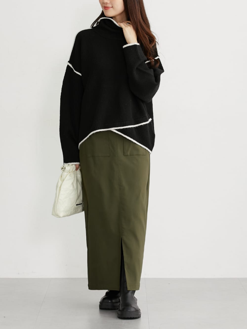 グリーン系のスカート、ブラック系のニット/セーターを着用したレディースの秋コーディネートの1枚目の写真