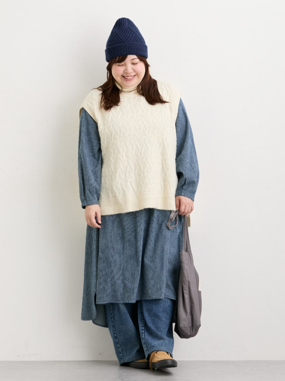 ブルー系のデニムパンツ、ベージュ系のニット/セーター、ブルー系のワンピースを着用したレディースの秋コーディネートの1枚目の写真