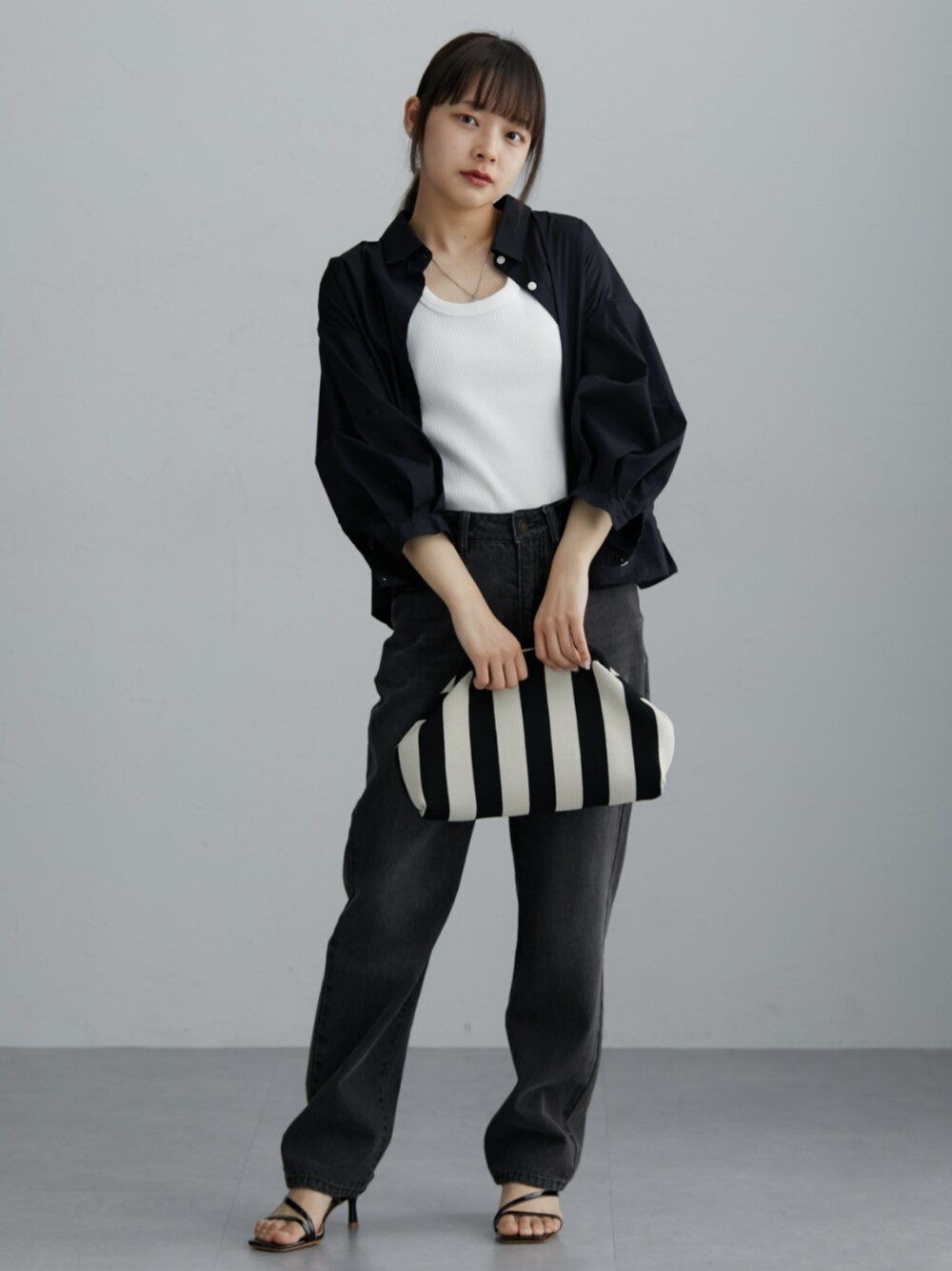 ブラック系のシャツ/ブラウス、グレー系のデニムパンツを着用したレディースの春コーディネートの1枚目の写真