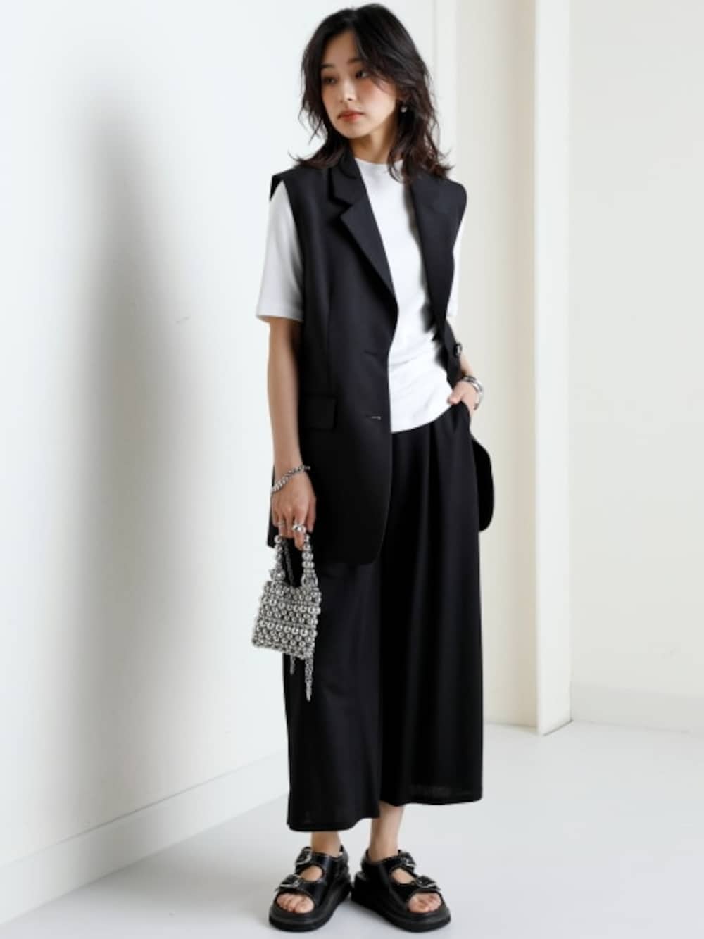 ホワイト系のTシャツ/カットソー、ブラック系のベスト、ブラック系のその他パンツを着用したレディースの春コーディネートの1枚目の写真