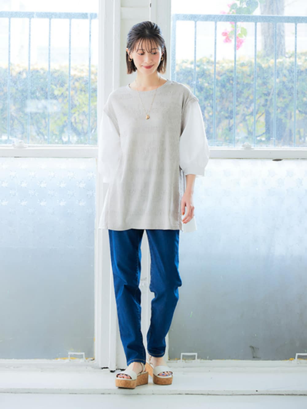 ブルー系のパンツ、ベージュ系のチュニックを着用したレディースの春コーディネートの1枚目の写真