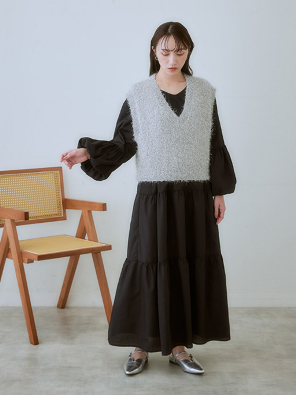 シルバー系のベスト、ブラック系のワンピースを着用したレディースの冬コーディネートの1枚目の写真