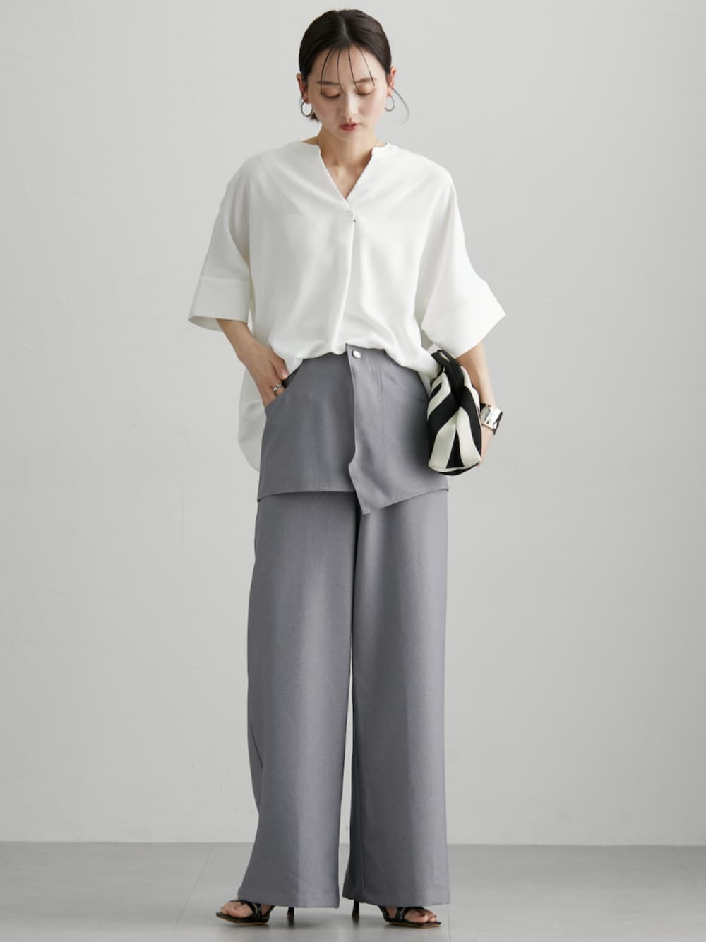 ホワイト系のシャツ/ブラウス、グレー系のパンツを着用したレディースの春コーディネートの1枚目の写真