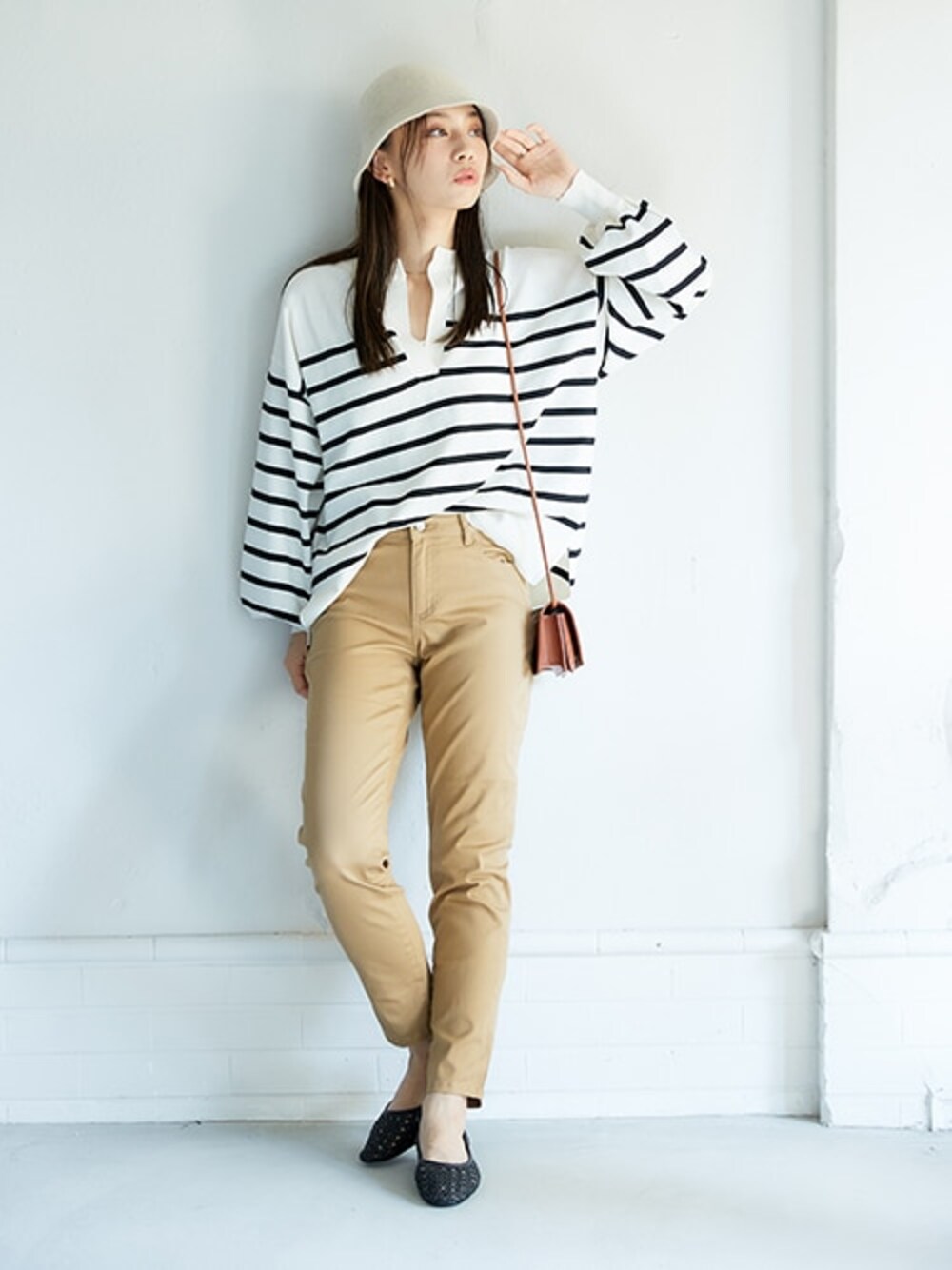 ベージュ系のパンツ、ホワイト系のニット/セーターを着用したレディースの冬コーディネートの1枚目の写真