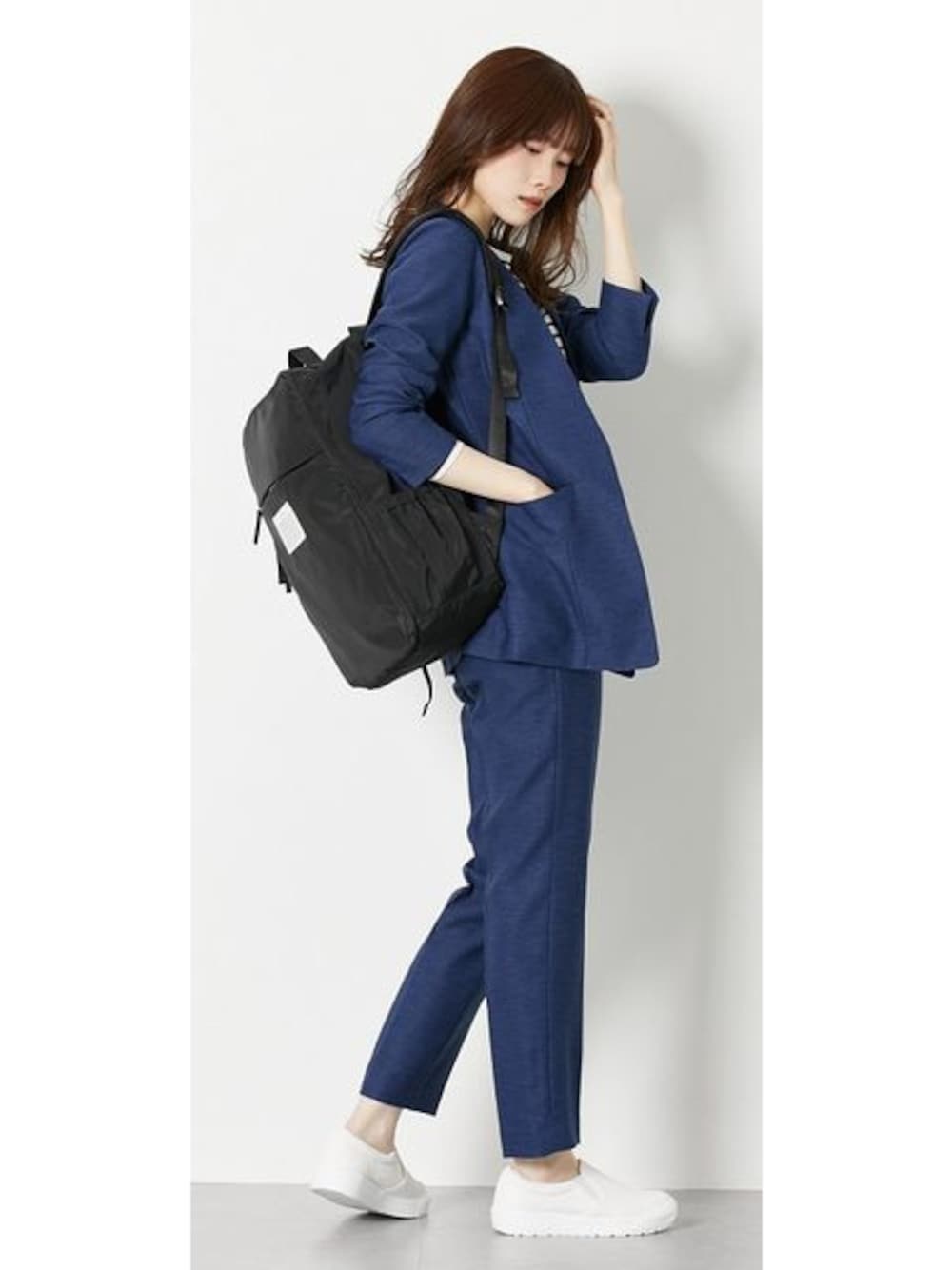 ブルー系のスーツセット、ホワイト系のスニーカー、ブラック系のバックパック/リュックを着用したレディースの春コーディネートの1枚目の写真