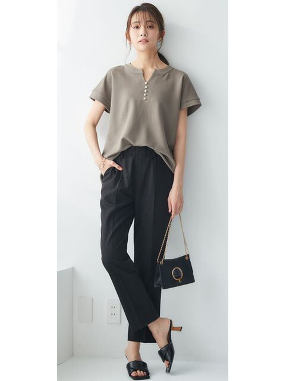 ブラック系のスラックス、ブラウン系のTシャツ/カットソーを着用したレディースの春コーディネートの1枚目の写真