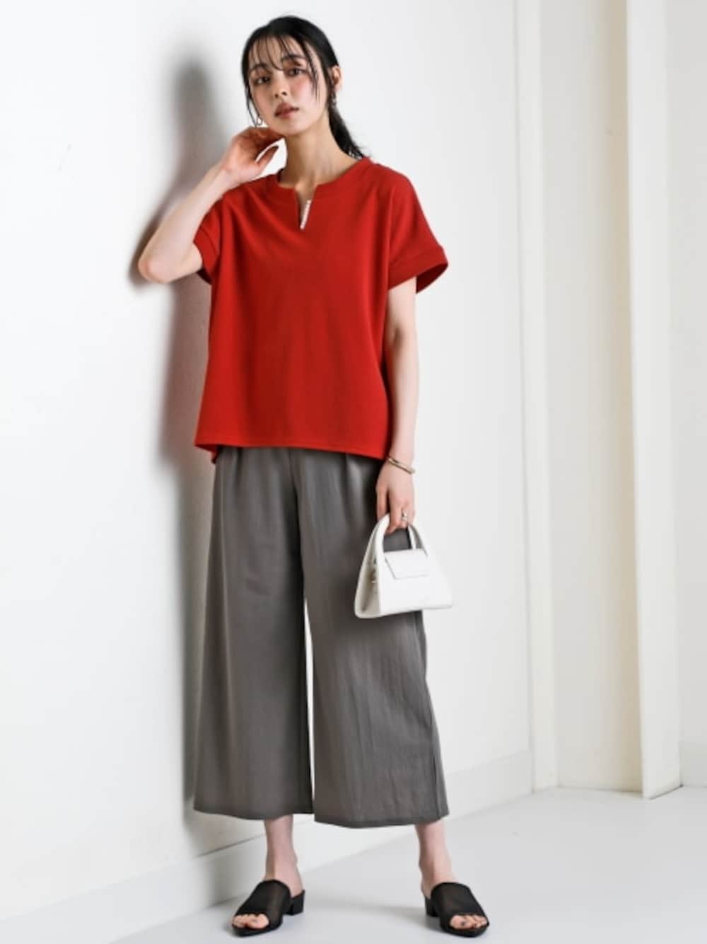 オレンジ系のTシャツ/カットソー、グレー系のパンツを着用したレディースの春コーディネートの1枚目の写真