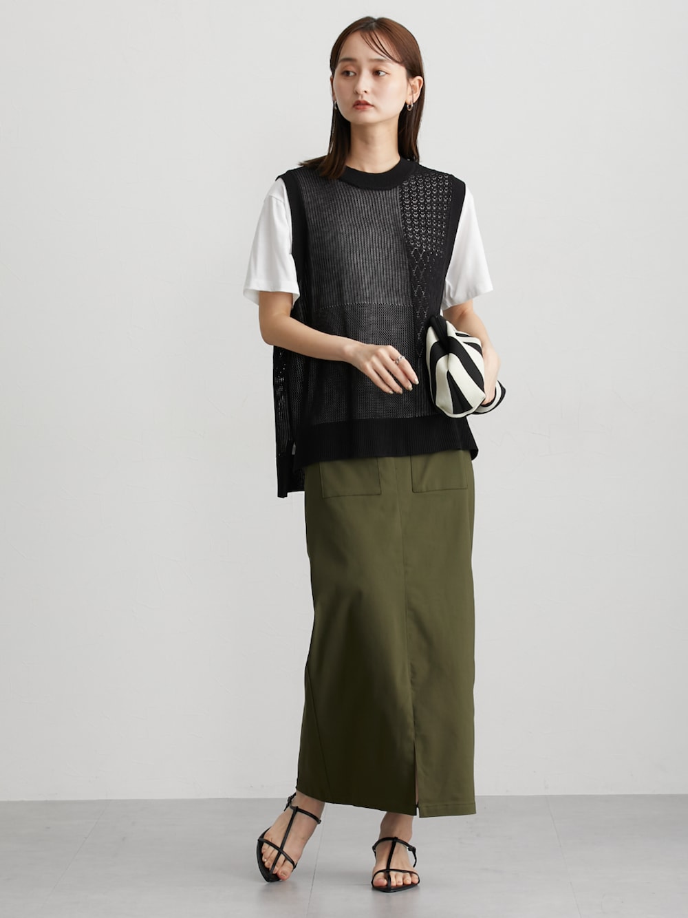 グリーン系のスカート、ブラック系のアンサンブルを着用したレディースの夏コーディネートの1枚目の写真