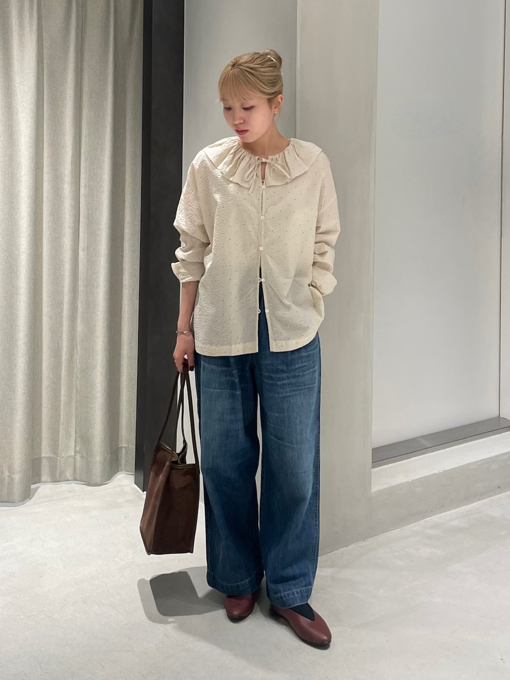 ブラウン系のパンプス、ブラウン系のトートバッグ、ブルー系のデニムパンツを着用したレディースの秋コーディネートの1枚目の写真
