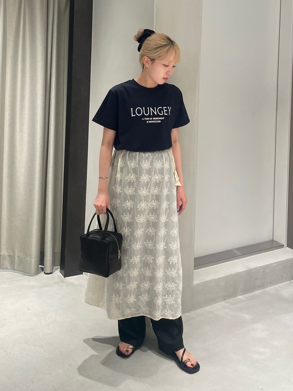 ブラック系のボストンバッグ、ブルー系のTシャツ/カットソー、ホワイト系のスカートを着用したレディースの夏コーディネートの1枚目の写真