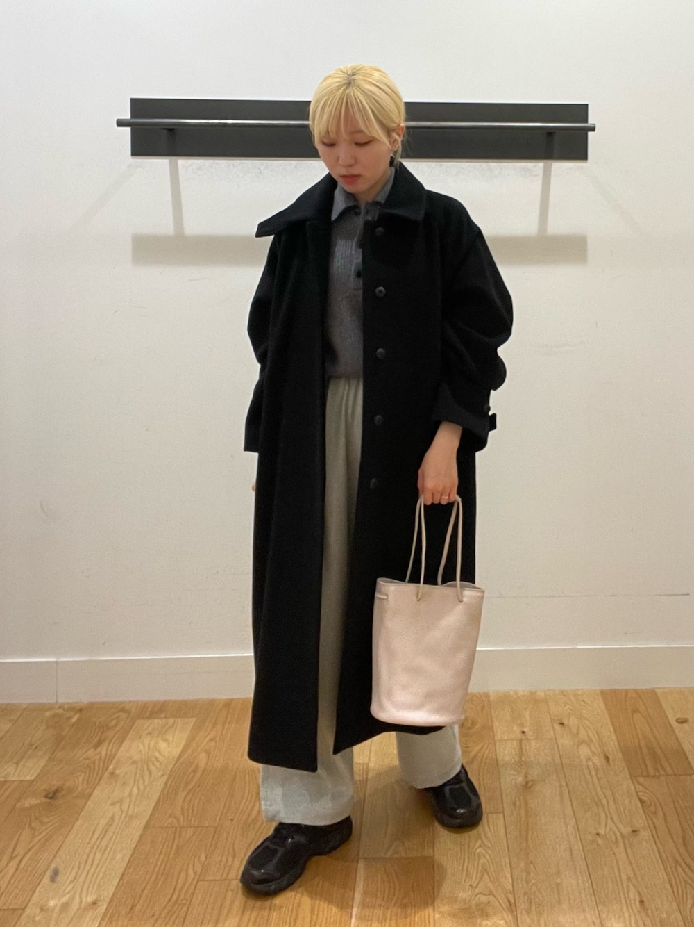 ブラック系のステンカラーコート、グレー系のニット/セーター、グレー系のその他パンツを着用したレディースの冬コーディネートの1枚目の写真