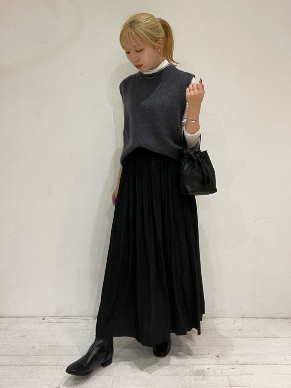 ブラック系のスカート、ブラック系のショルダーバッグ、ブラック系のブーツを着用したレディースの秋コーディネートの1枚目の写真