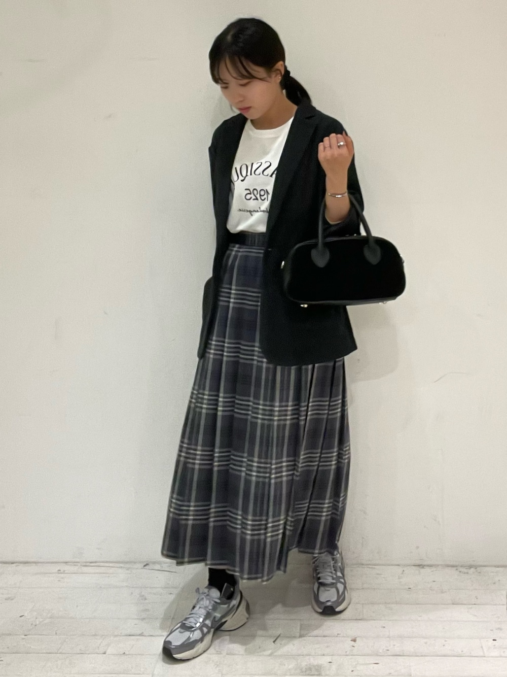 グレー系のスカート、ブラック系のショルダーバッグ、ホワイト系のTシャツ/カットソーを着用したレディースの秋コーディネートの1枚目の写真