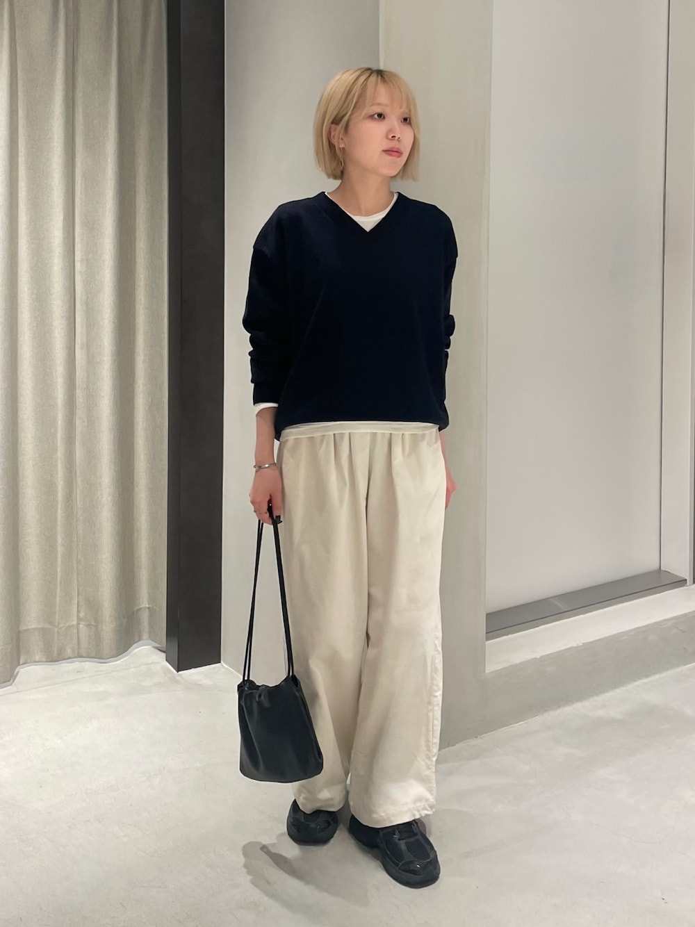 ブラック系のスニーカー、ブルー系のニット/セーター、ホワイト系のTシャツ/カットソーを着用したレディースの秋コーディネートの1枚目の写真
