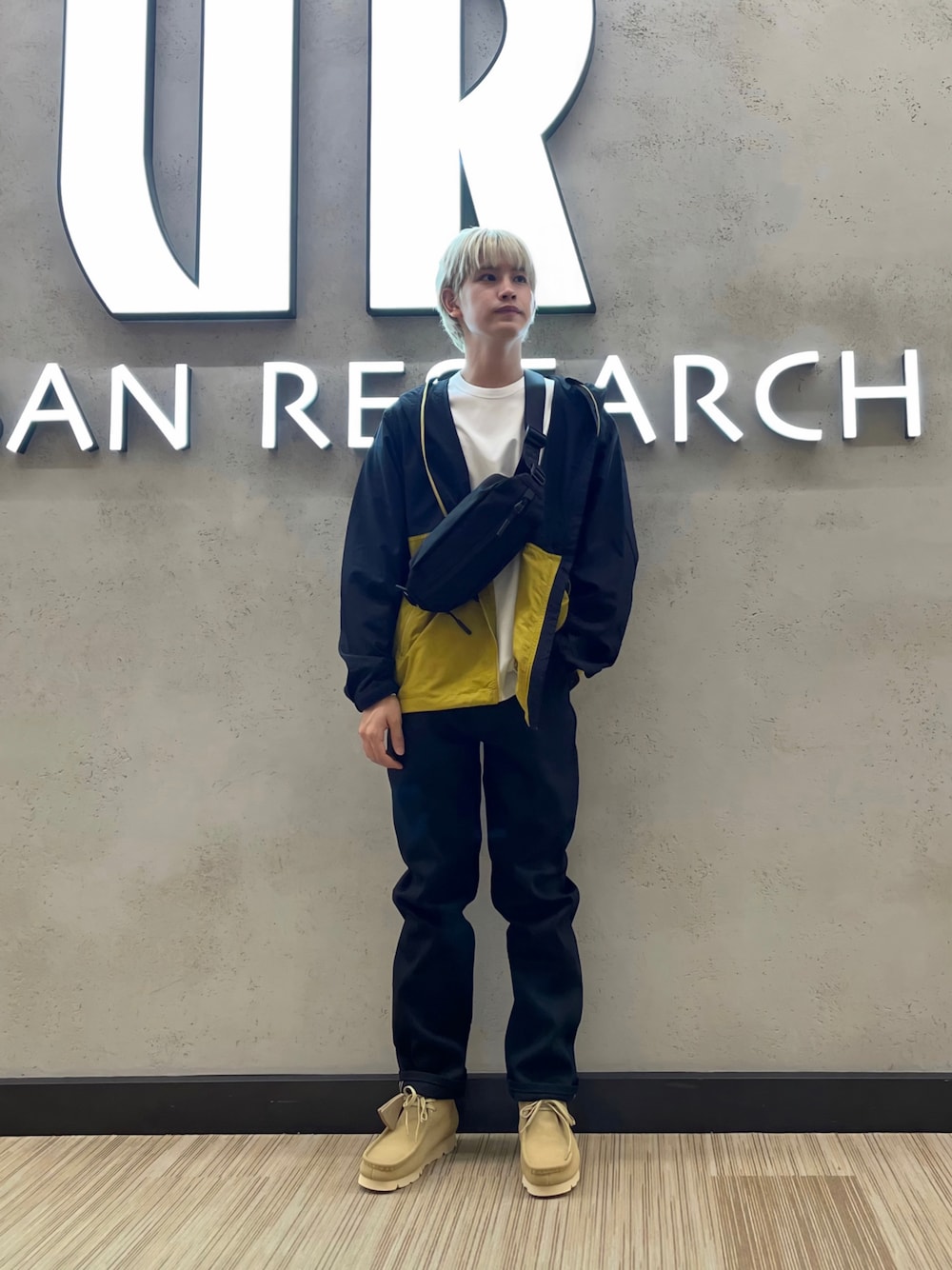 ブラック系のデニムパンツ、ベージュ系のスニーカー、イエロー系のマウンテンパーカーを着用したメンズの秋コーディネートの1枚目の写真