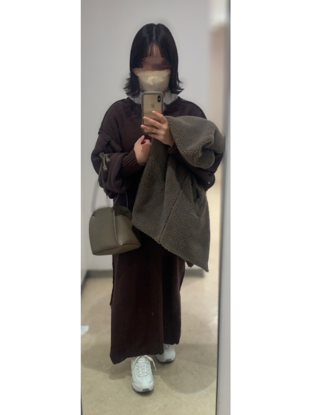 ブラウン系のワンピース、ベージュ系のハンドバッグ、ホワイト系のスニーカーを着用したレディースの冬コーディネートの1枚目の写真