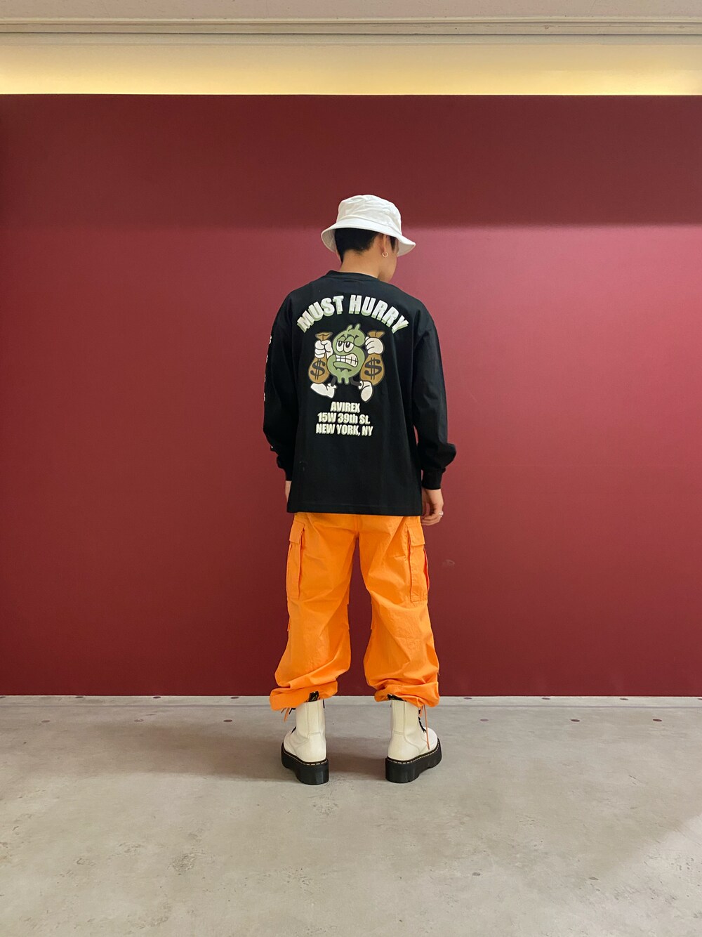 ブラック系のTシャツ/カットソー、オレンジ系のカーゴパンツ、ホワイト系のハットを着用したメンズの冬コーディネートの1枚目の写真