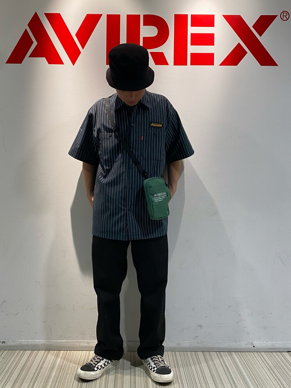 グリーン系のショルダーバッグ、ブラック系のチノパンツ、グリーン系のシャツ/ブラウスを着用したメンズの春コーディネートの1枚目の写真