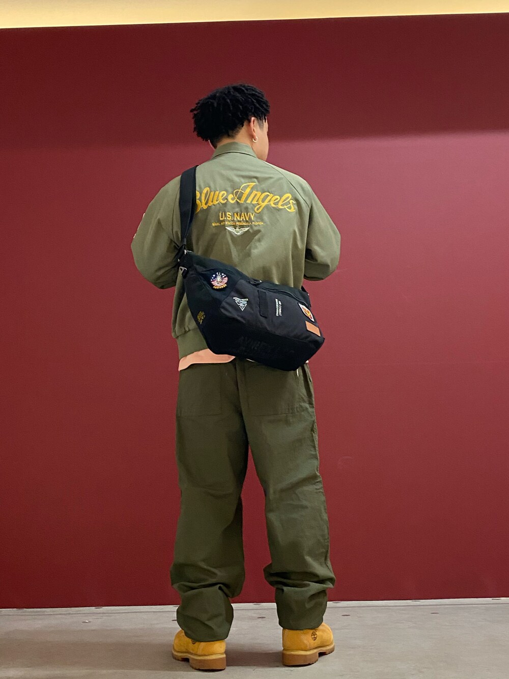 グリーン系のミリタリージャケット、ブラック系のショルダーバッグ、グリーン系のカーゴパンツを着用したメンズの春コーディネートの1枚目の写真