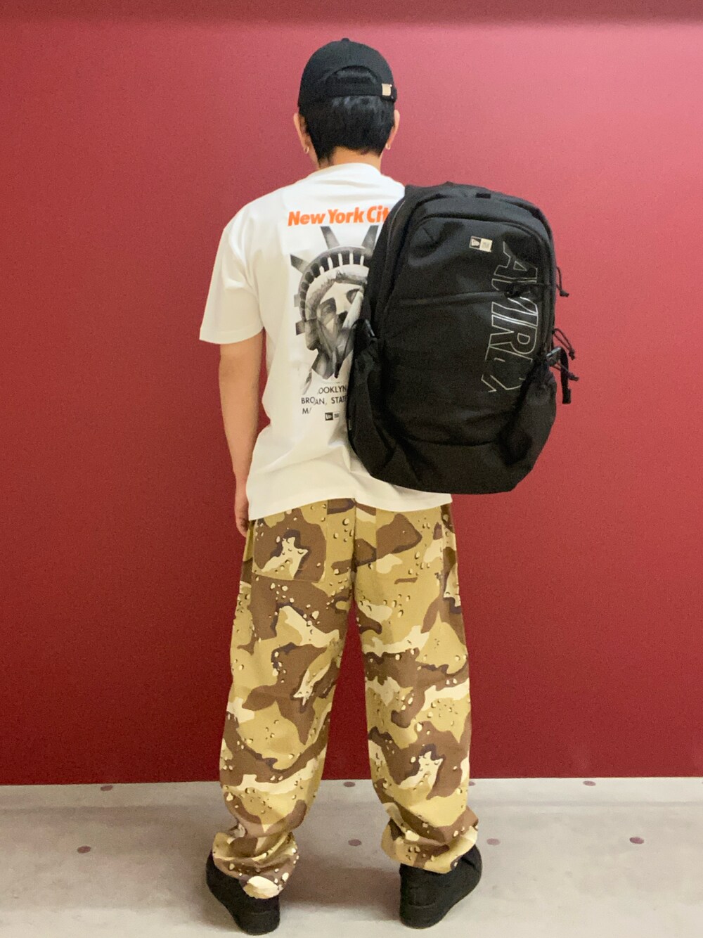 ブラック系のバックパック/リュック、ホワイト系のTシャツ/カットソー、その他のパンツを着用したメンズの春コーディネートの1枚目の写真