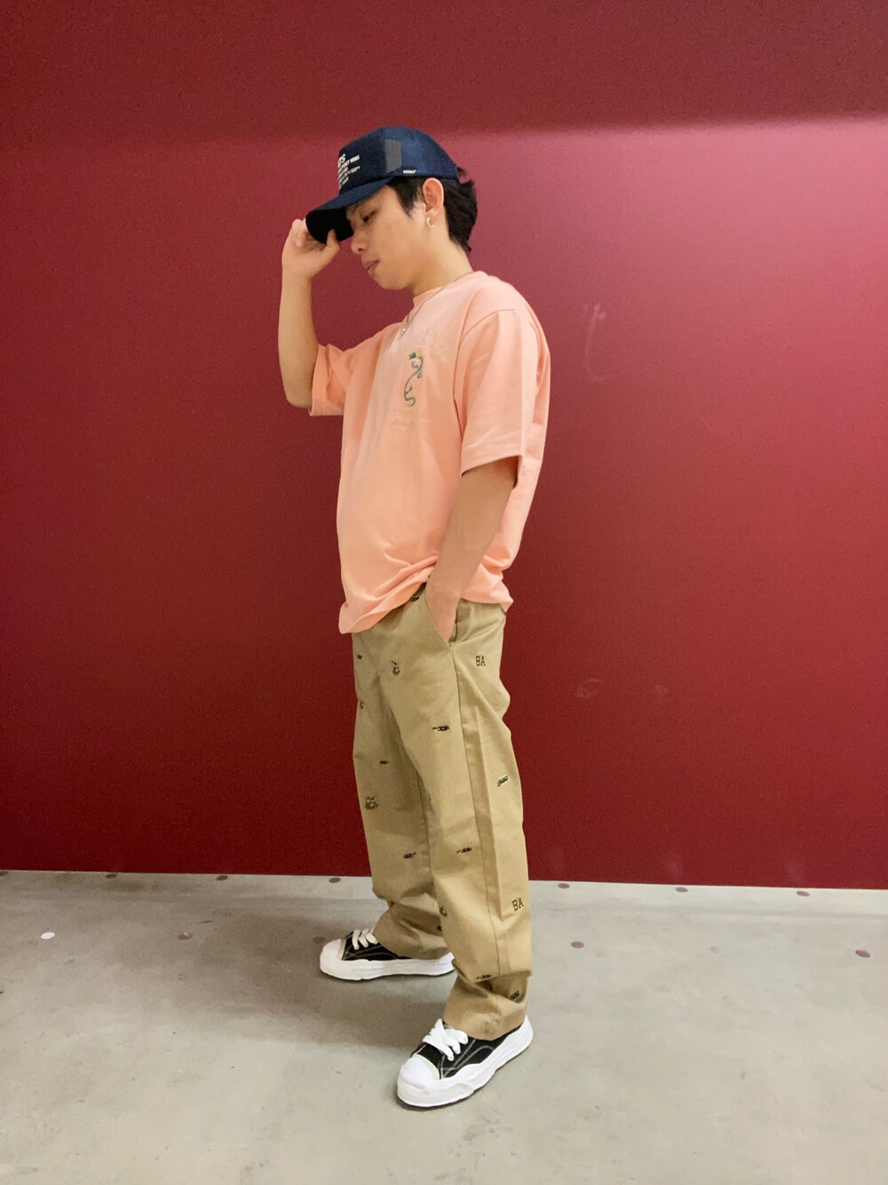 ピンク系のTシャツ/カットソー、グリーン系のチノパンツ、ブルー系のキャップを着用したメンズの春コーディネートの1枚目の写真