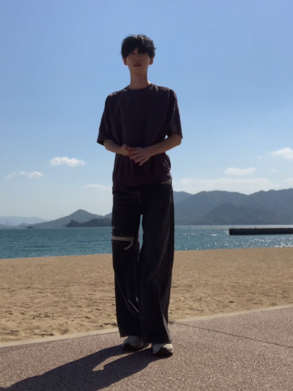 グレー系のTシャツ/カットソー、ブラック系のデニムパンツ、ホワイト系のスニーカーを着用したメンズの春コーディネートの1枚目の写真