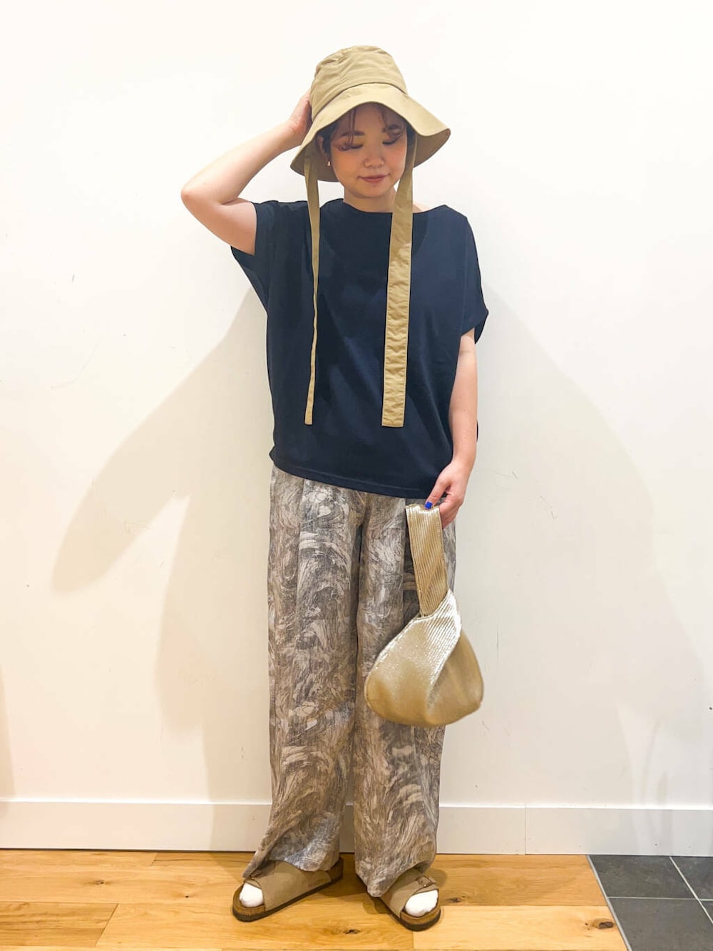 ブルー系のTシャツ/カットソー、ゴールド系のハンドバッグ、ベージュ系のサンダルを着用したレディースの夏コーディネートの1枚目の写真