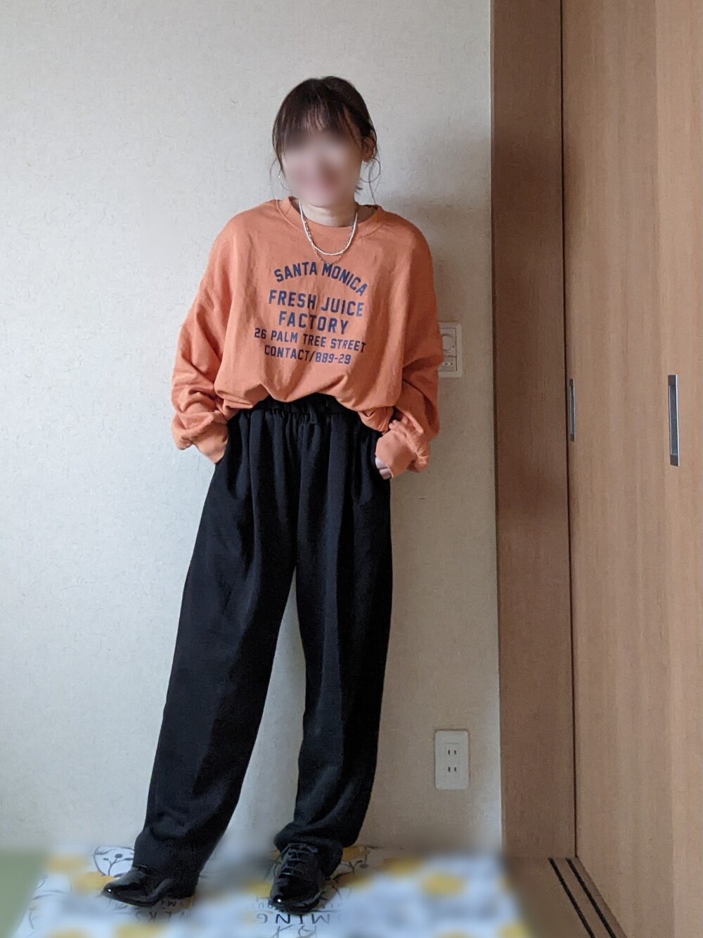 ブラック系のスウェットパンツ、ブラック系のベスト、オレンジ系のスウェットを着用したレディースの春コーディネートの5枚目の写真