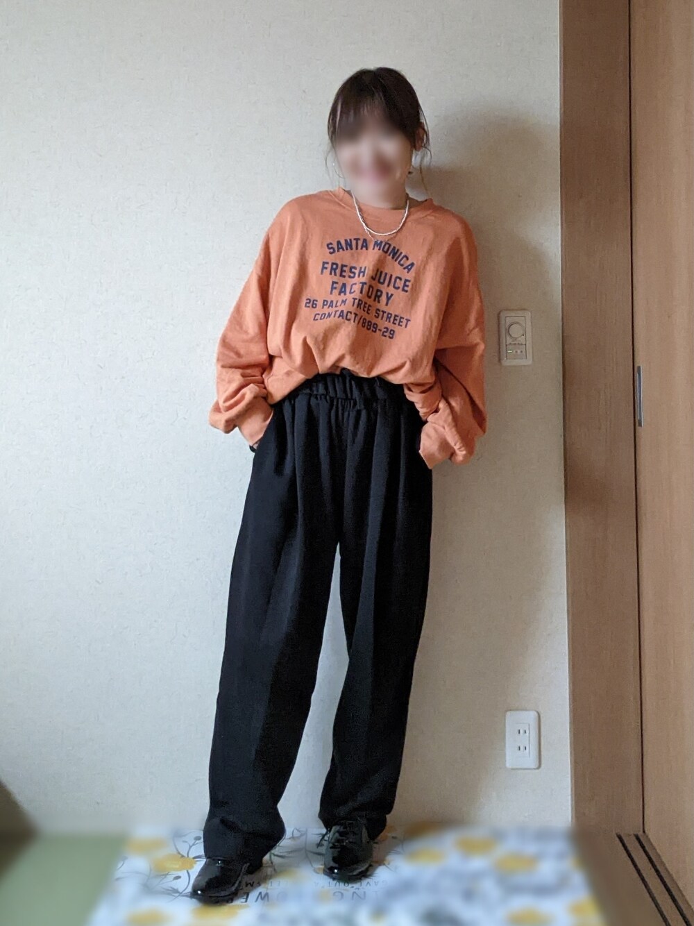 ブラック系のスウェットパンツ、ブラック系のベスト、オレンジ系のスウェットを着用したレディースの春コーディネートの2枚目の写真