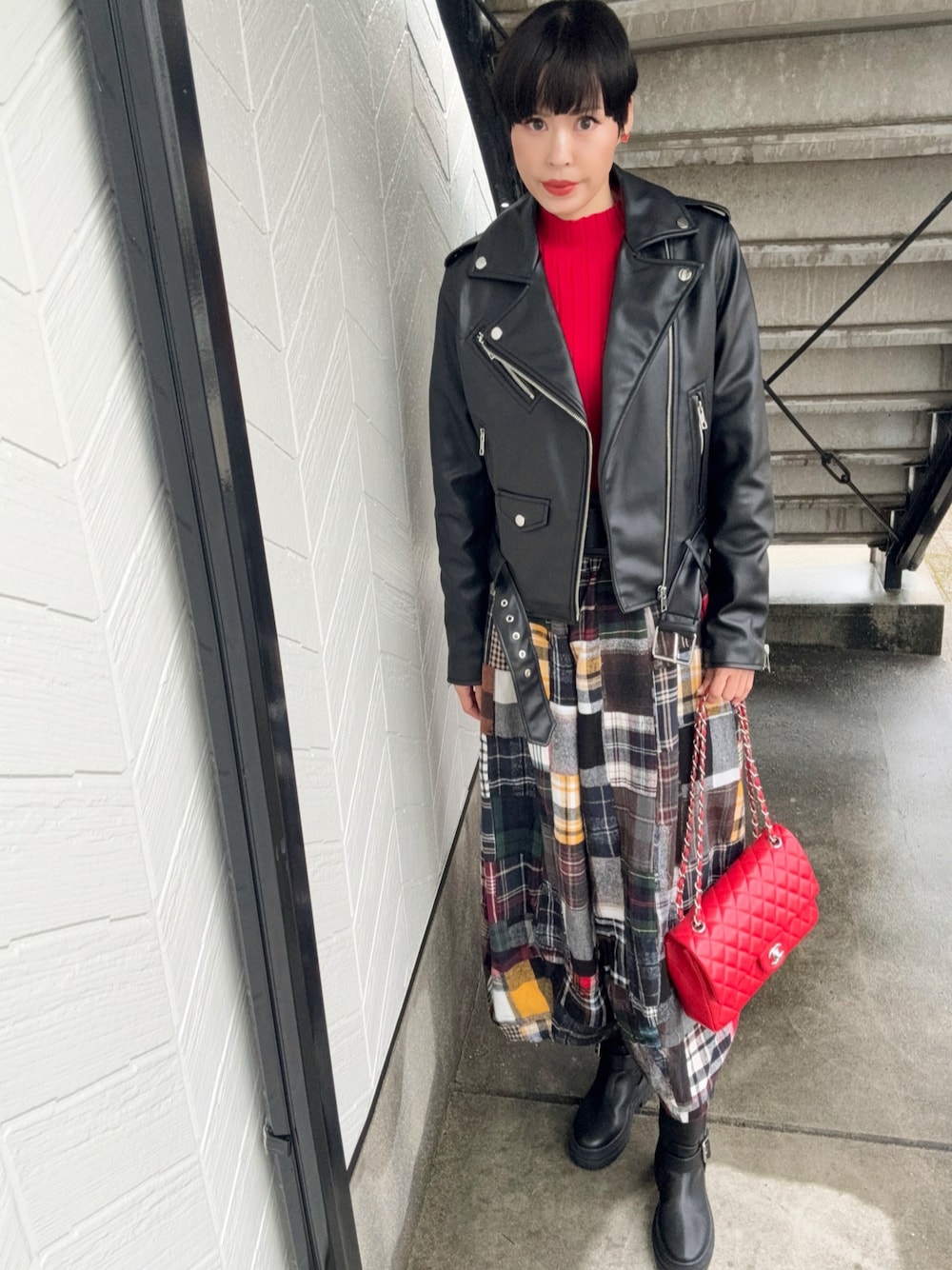 ブラック系のブーツ、ブラック系のライダースジャケット、レッド系のショルダーバッグを着用したレディースの秋コーディネートの1枚目の写真
