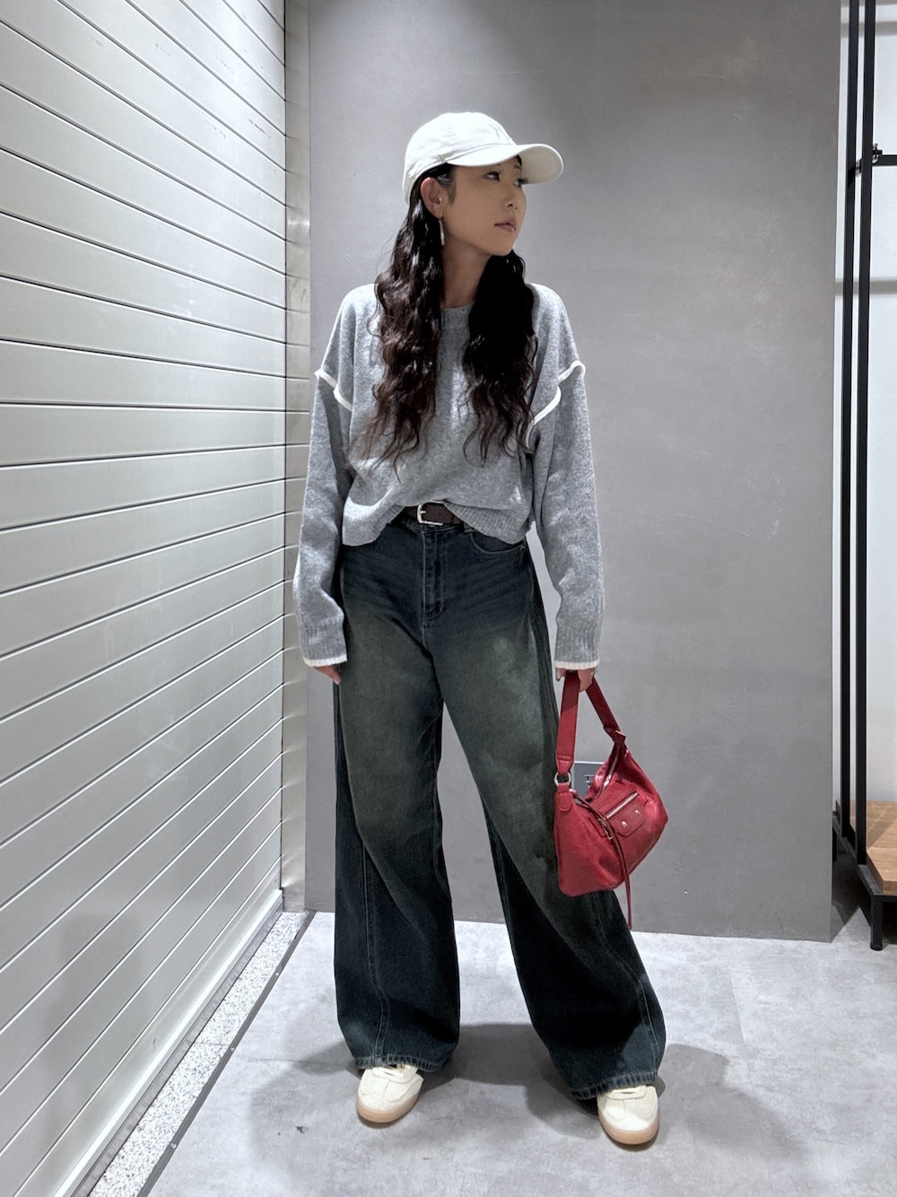 ブルー系のデニムパンツ、グレー系のニット/セーター、レッド系のショルダーバッグを着用したレディースの秋コーディネートの1枚目の写真