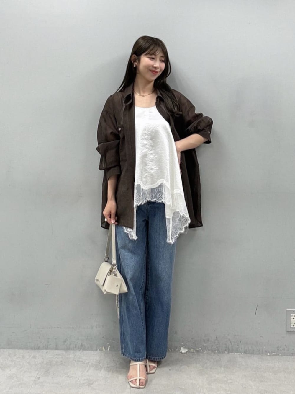 ホワイト系のショルダーバッグ、ブラウン系のシャツ/ブラウス、ブルー系のデニムパンツを着用したレディースの夏コーディネートの1枚目の写真