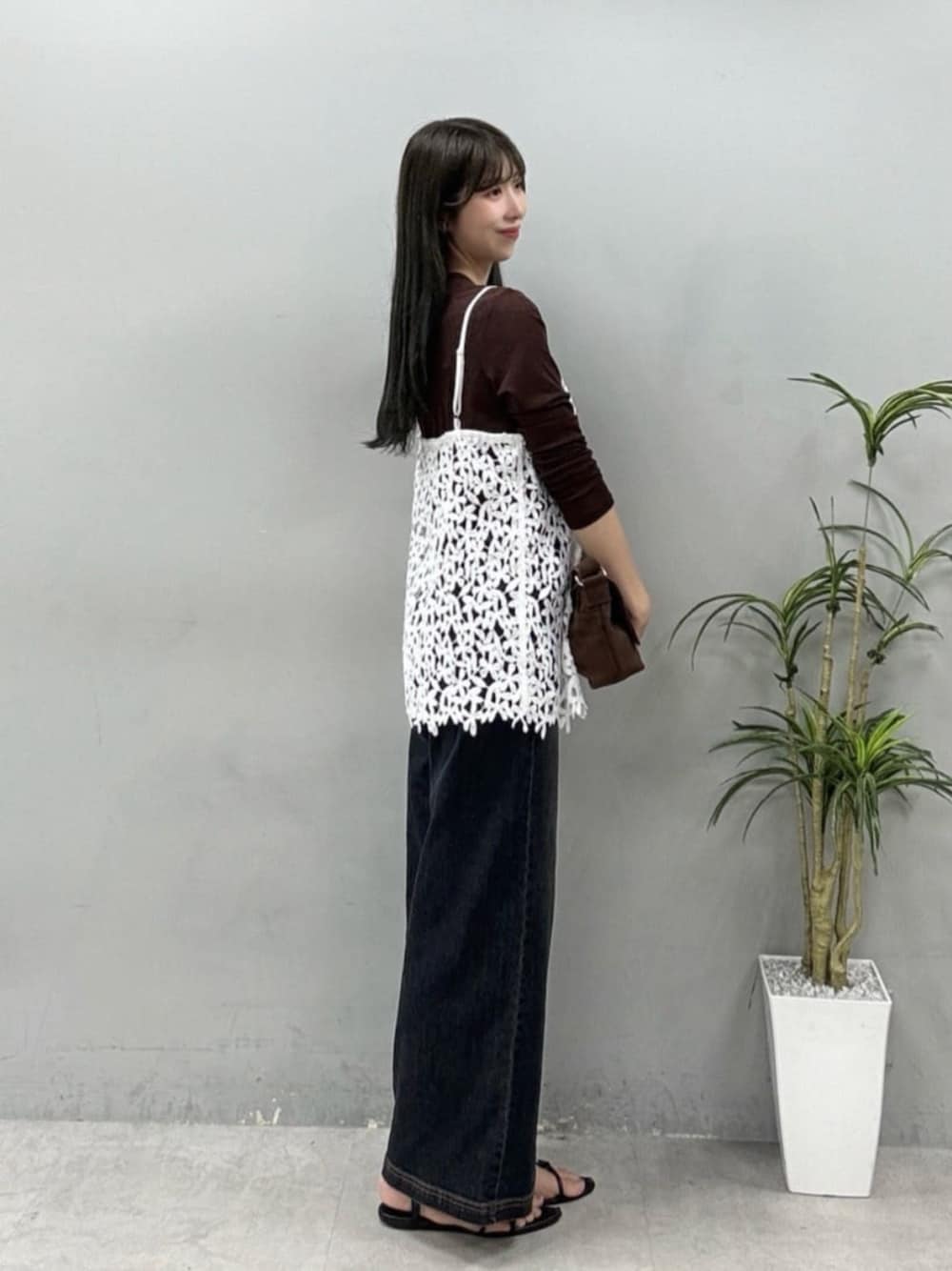 ブラウン系のショルダーバッグ、ブルー系のデニムパンツ、ホワイト系のキャミソールを着用したレディースの夏コーディネートの1枚目の写真