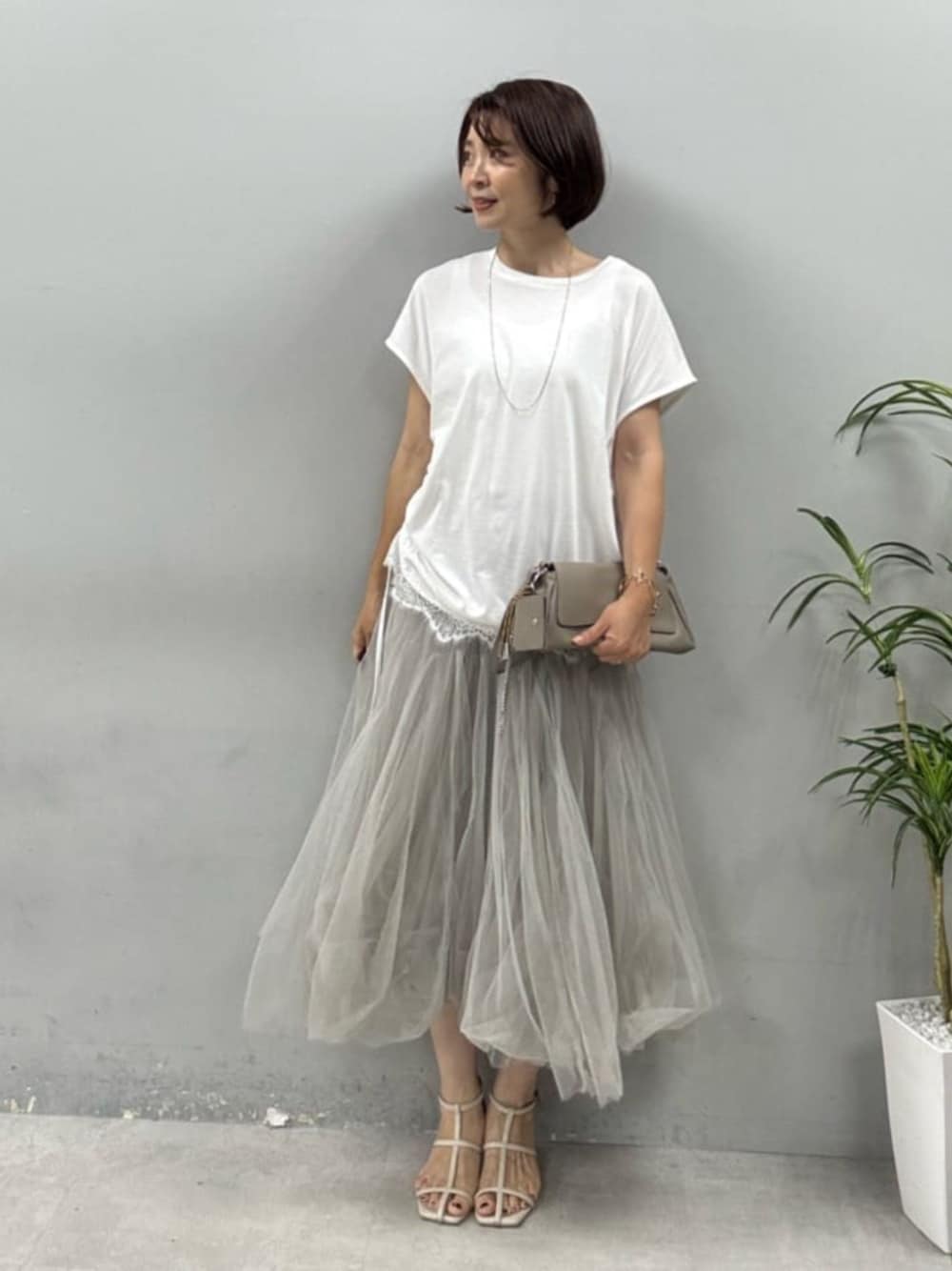 ベージュ系のショルダーバッグ、ホワイト系のTシャツ/カットソー、ベージュ系のスカートを着用したレディースの夏コーディネートの1枚目の写真