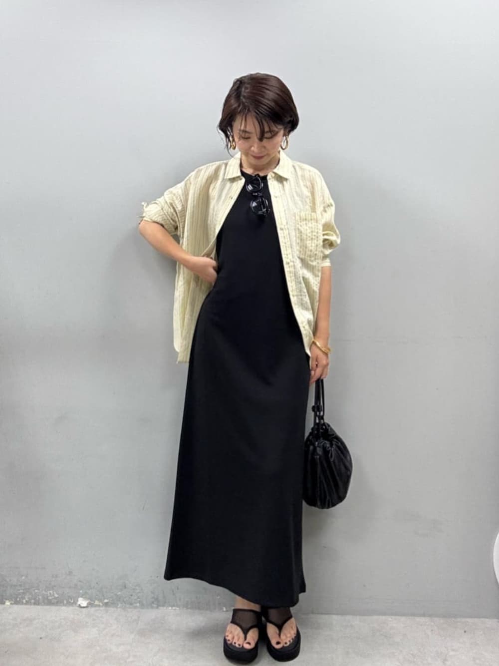 ブラック系のワンピース、イエロー系のシャツ/ブラウスを着用したレディースの春コーディネートの1枚目の写真