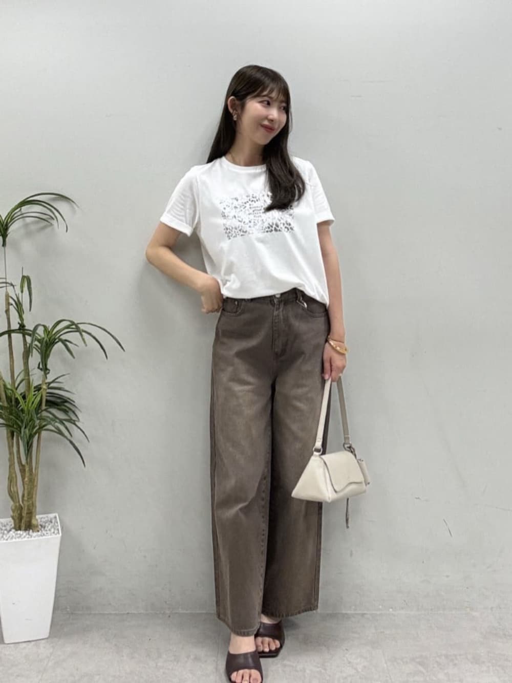 ホワイト系のショルダーバッグ、ブラウン系のデニムパンツを着用したレディースの夏コーディネートの1枚目の写真