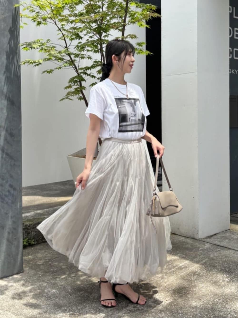 ベージュ系のショルダーバッグ、ホワイト系のTシャツ/カットソー、ベージュ系のスカートを着用したレディースの夏コーディネートの1枚目の写真