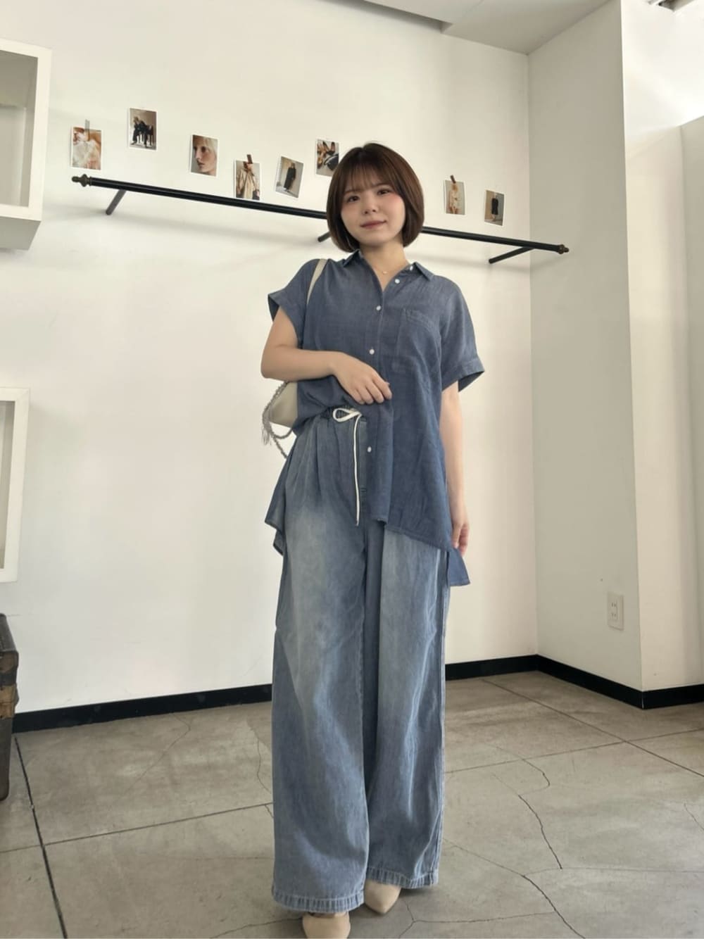 ホワイト系のショルダーバッグ、ブルー系のシャツ/ブラウス、ブルー系のデニムパンツを着用したレディースの夏コーディネートの1枚目の写真