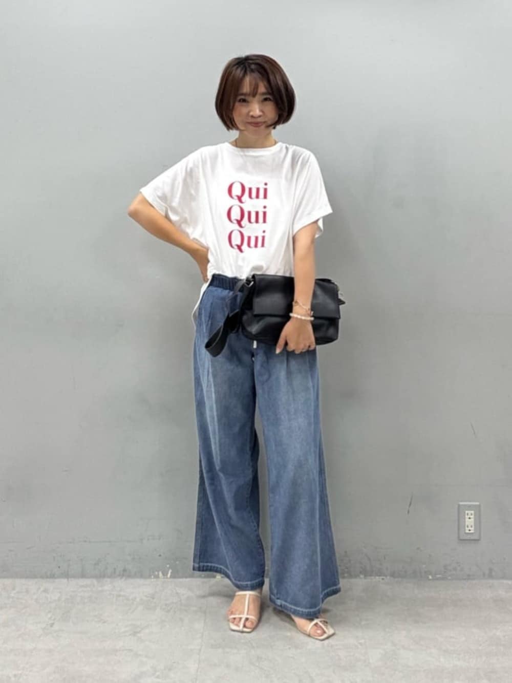 ブラック系のショルダーバッグ、ホワイト系のTシャツ/カットソー、ブルー系のデニムパンツを着用したレディースの夏コーディネートの1枚目の写真